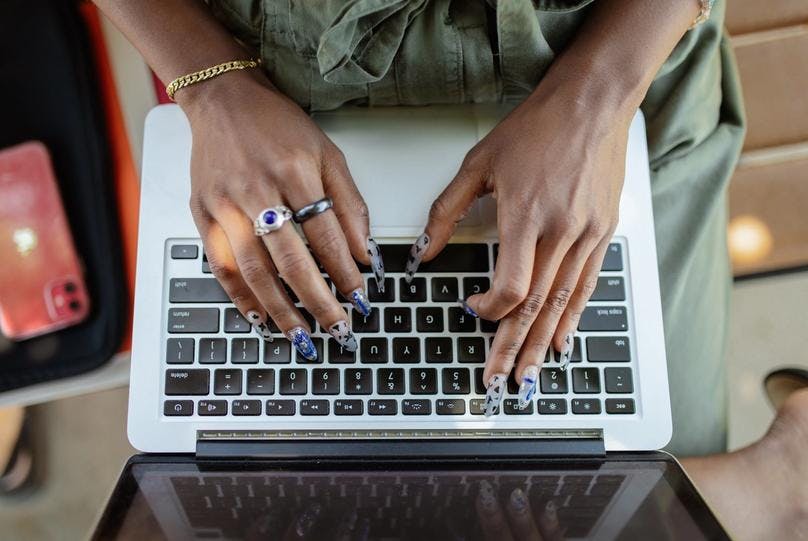 A woman, having long nails, typing something on her laptop