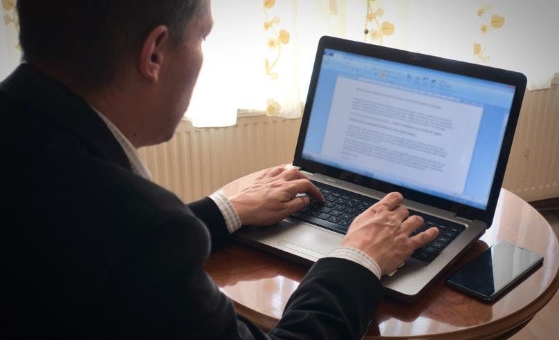 person typing essay on his laptop