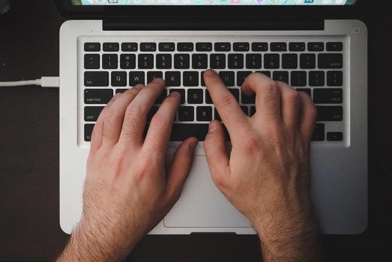 A man is typing on his laptop using both of his hands