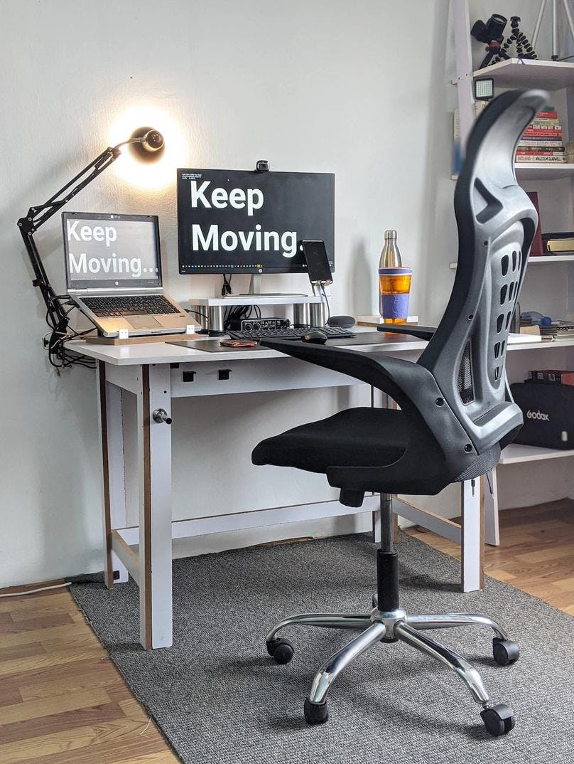 A computer desk with a laptop, desktop, and chair representing a perfect typing ergonomics to get the best touch typing benefits
