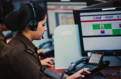 A 911 dispatcher communicating with a caller while typing on her keyboard