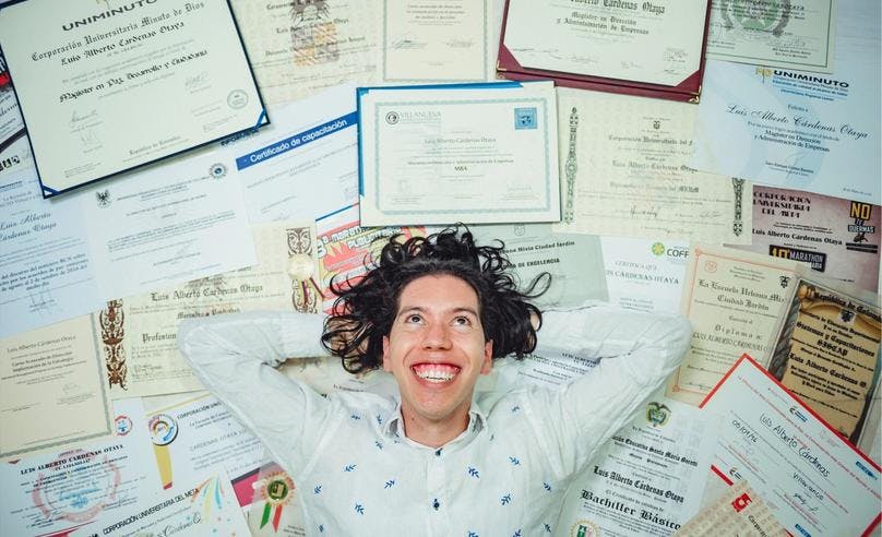 Man lying on a large amount of certificates he earned in his lifetime
