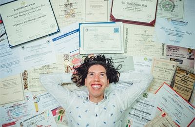 Man lying on a large amount of certificates he earned in his lifetime