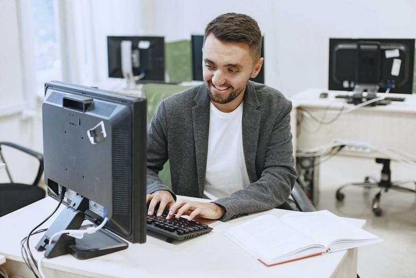 A man typing on a desktop computer 