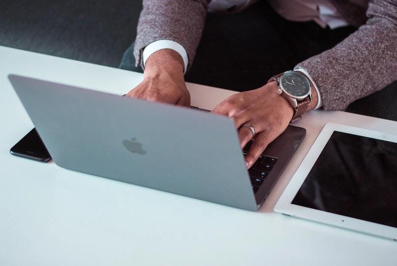 A gentleman is typing on his apple MacBook