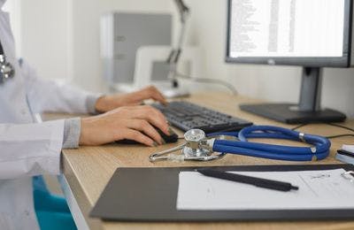 A doctor typing medical and healthcare terminologies on his desktop computer keyboard